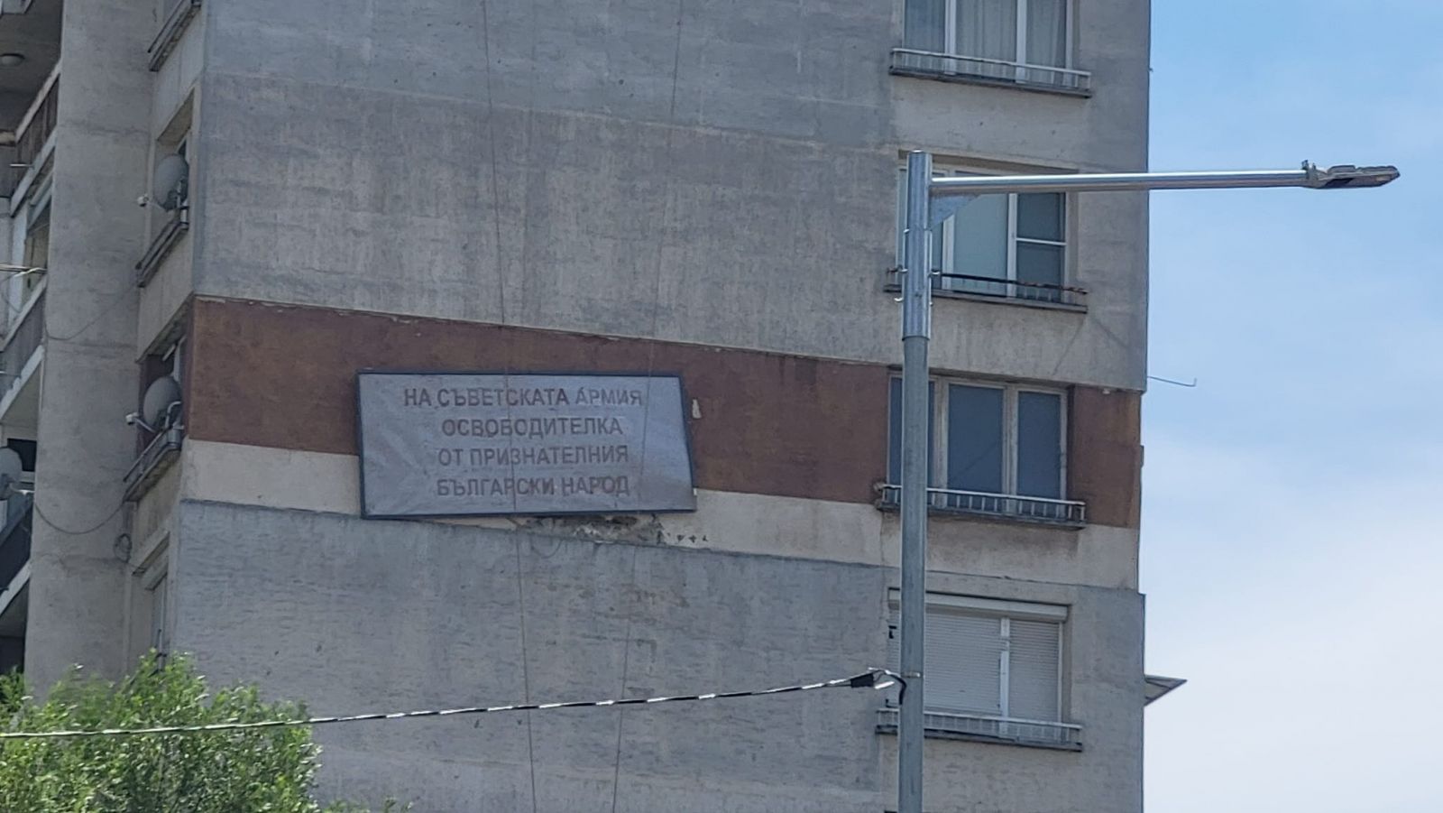 Мъж монтира на блока си  плоча с надпис 
